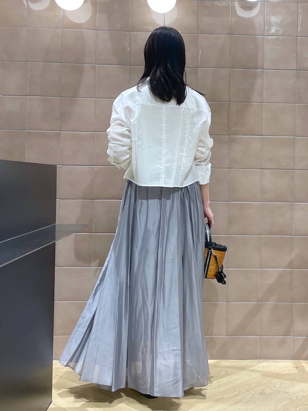 ホワイト系のタンクトップ、ブラック系のサンダル、グレー系のスカートを着用したレディースの春コーディネートの3枚目の写真