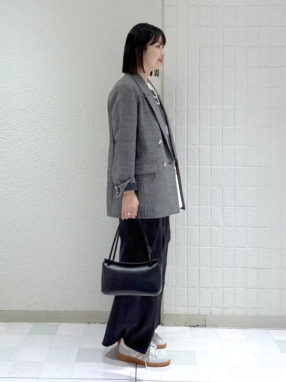 シルバー系のスニーカー、ブラック系のテーラードジャケット、ブラック系のショルダーバッグを着用したレディースの冬コーディネートの3枚目の写真