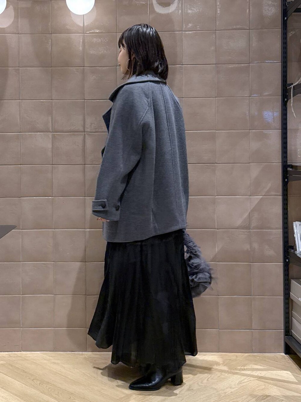 グレー系のピーコート、グレー系のニット/セーター、ブラック系のスカートを着用したレディースの冬コーディネートの4枚目の写真