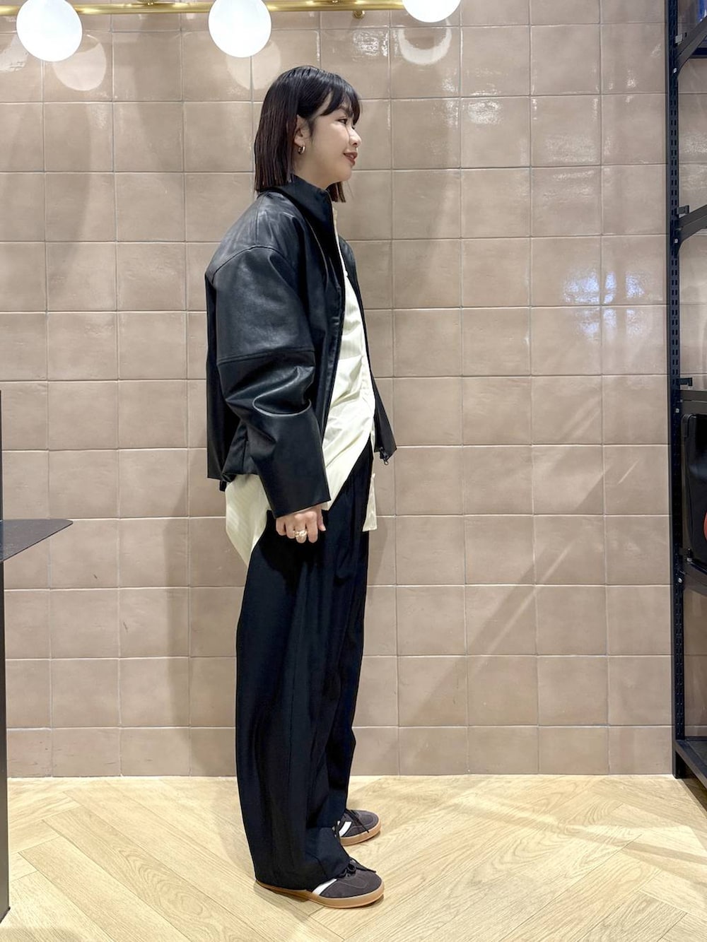 ブラック系のスラックス、ブラック系のブルゾン、イエロー系のシャツ/ブラウスを着用したレディースの冬コーディネートの3枚目の写真