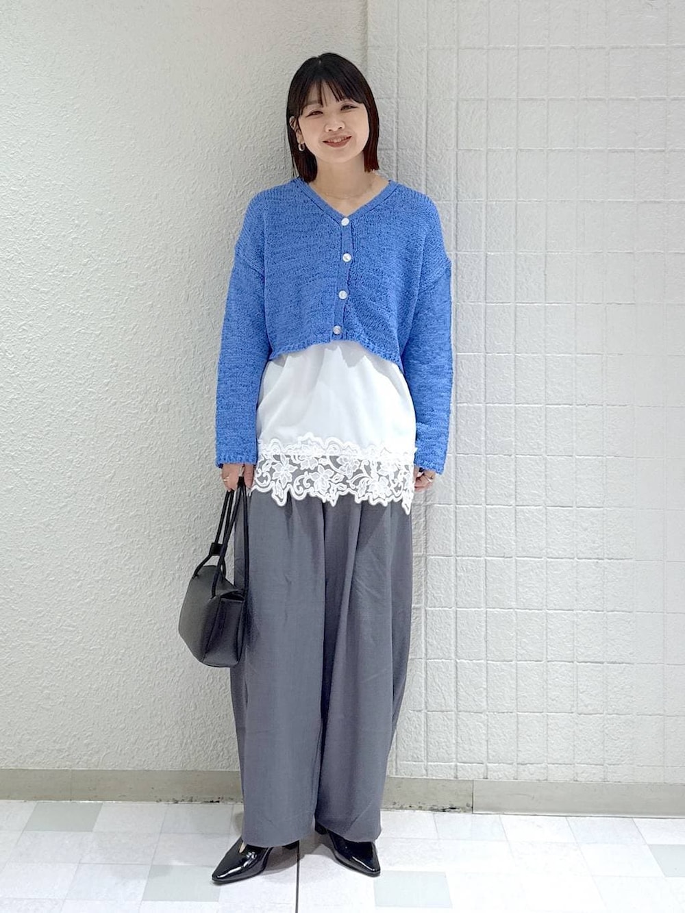 グレー系のスラックス、ホワイト系のキャミソール、ブラック系のパンプスを着用したレディースの春コーディネートの2枚目の写真