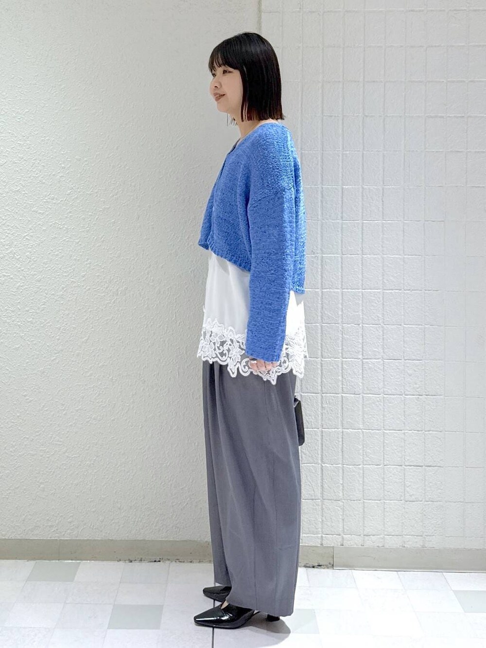 グレー系のスラックス、ホワイト系のキャミソール、ブラック系のパンプスを着用したレディースの春コーディネートの5枚目の写真