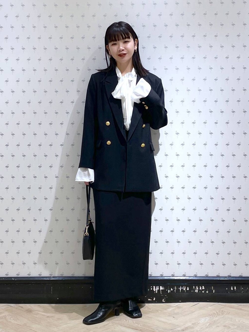 ブラック系のショルダーバッグ、ブラック系のブーツ、ブラック系のスカートを着用したレディースの冬コーディネートの2枚目の写真