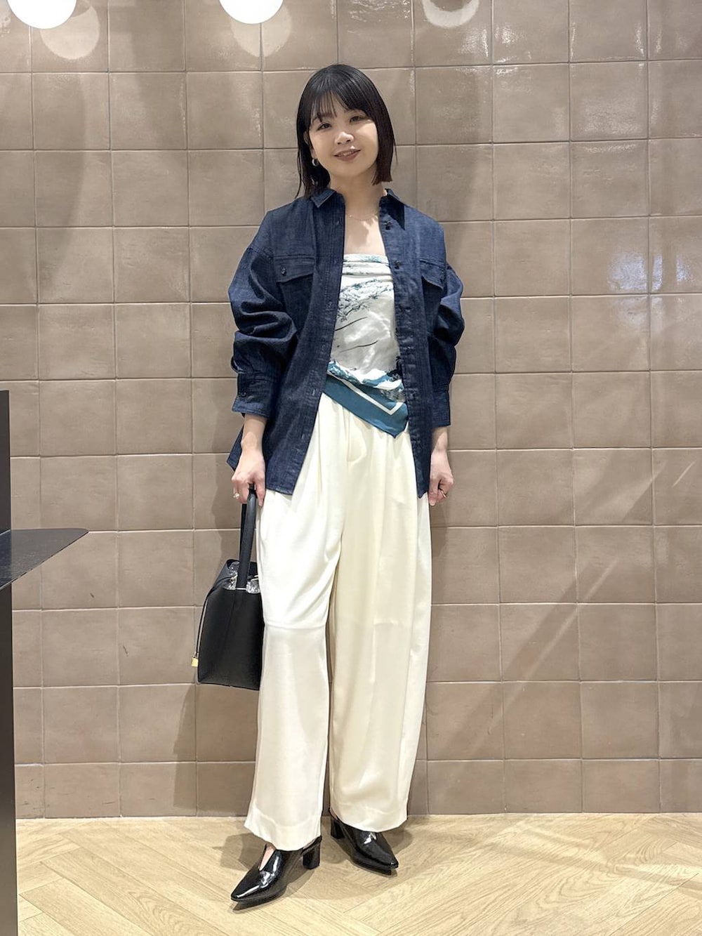 ホワイト系のスラックス、ブラック系のパンプス、ブラック系のショルダーバッグを着用したレディースの春コーディネートの3枚目の写真