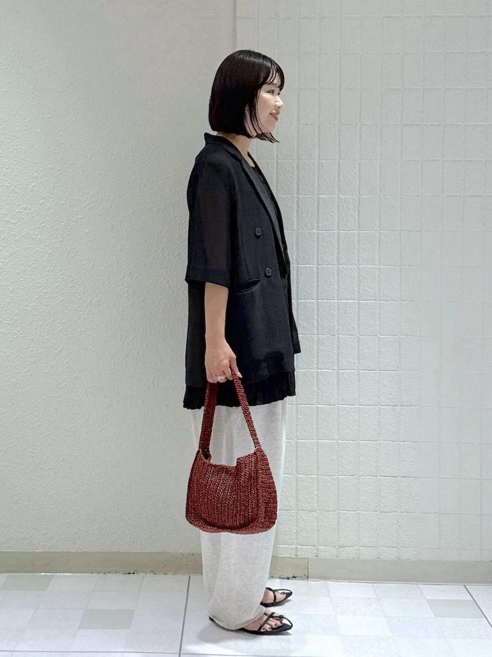 ブラック系のサンダル、ブラウン系のハンドバッグ、グレー系のスウェットパンツを着用したレディースの夏コーディネートの2枚目の写真