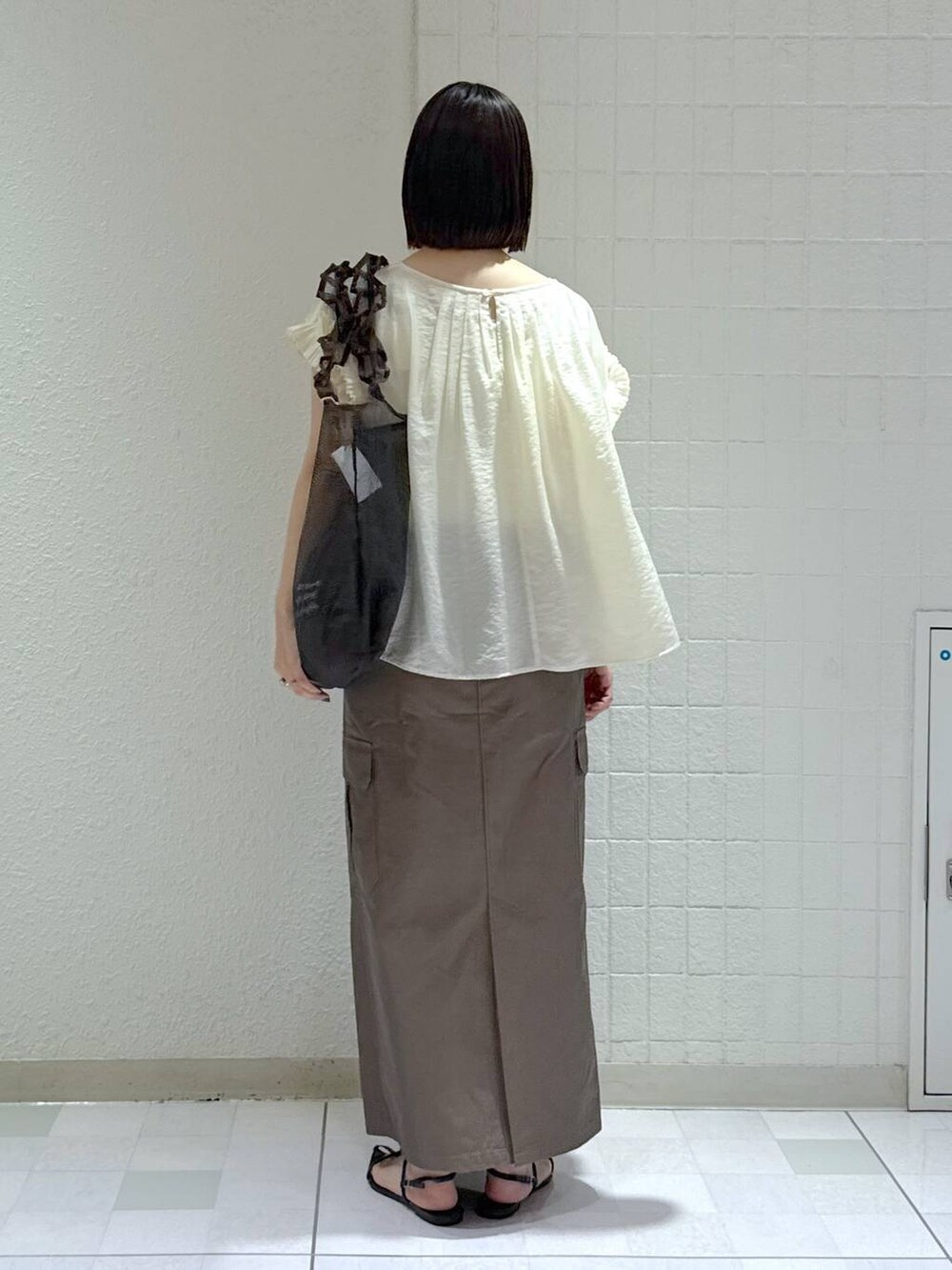 ブラック系のサンダル、ブラック系のトートバッグ、グリーン系のスカートを着用したレディースの夏コーディネートの4枚目の写真