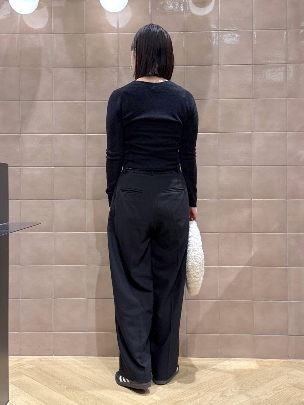 ブラック系のカーディガン/ボレロ、ホワイト系のハンドバッグ、ブラック系のスラックスを着用したレディースの秋コーディネートの2枚目の写真