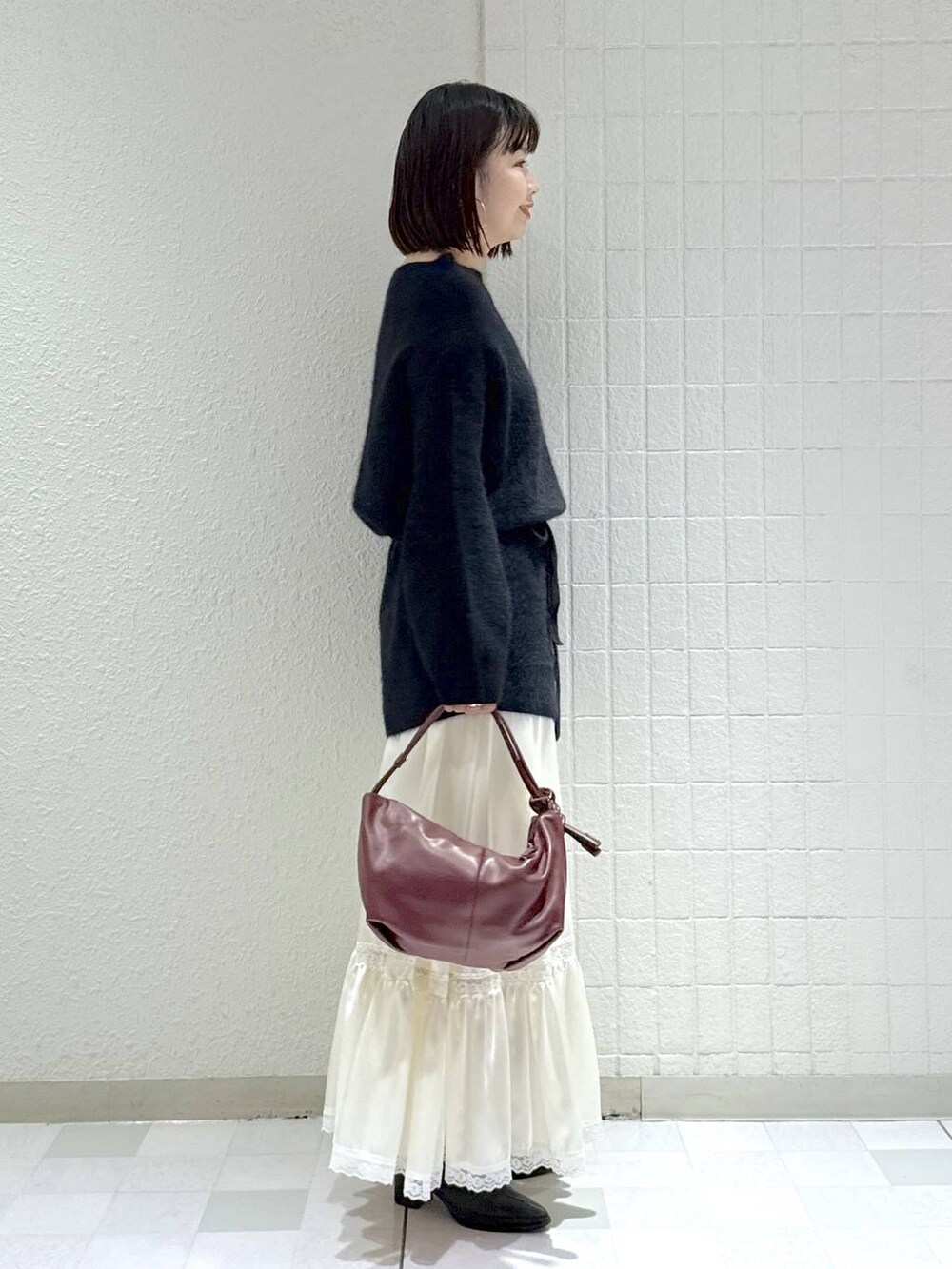 ブラック系のブーツ、ブラック系のワンピース、ホワイト系のスカートを着用したレディースの秋コーディネートの2枚目の写真