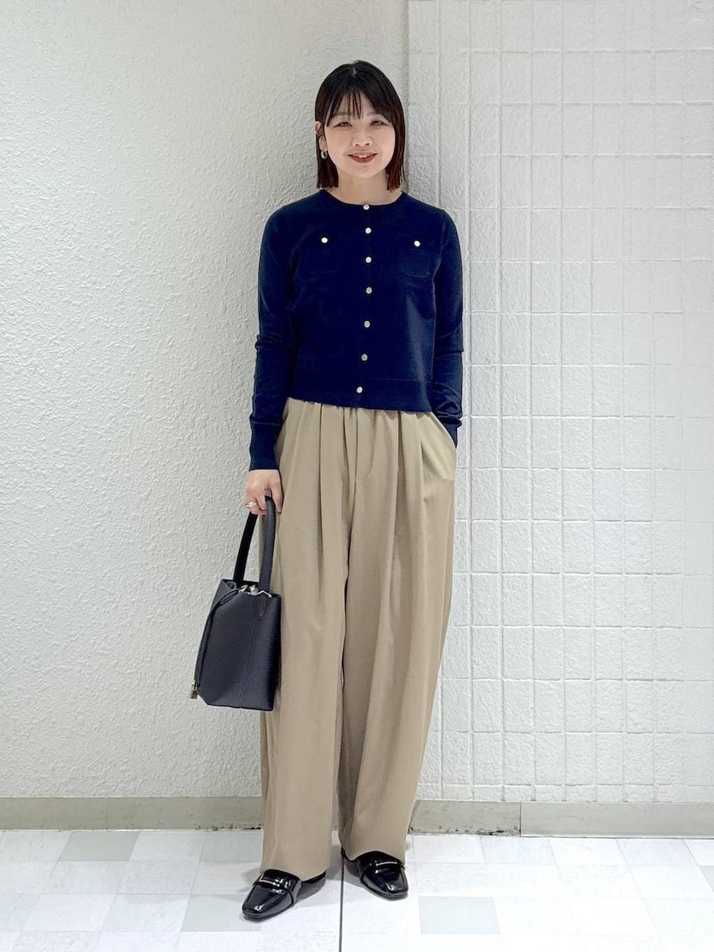 ベージュ系のスラックス、ブラック系のローファー、ブルー系のカーディガン/ボレロを着用したレディースの冬コーディネートの2枚目の写真