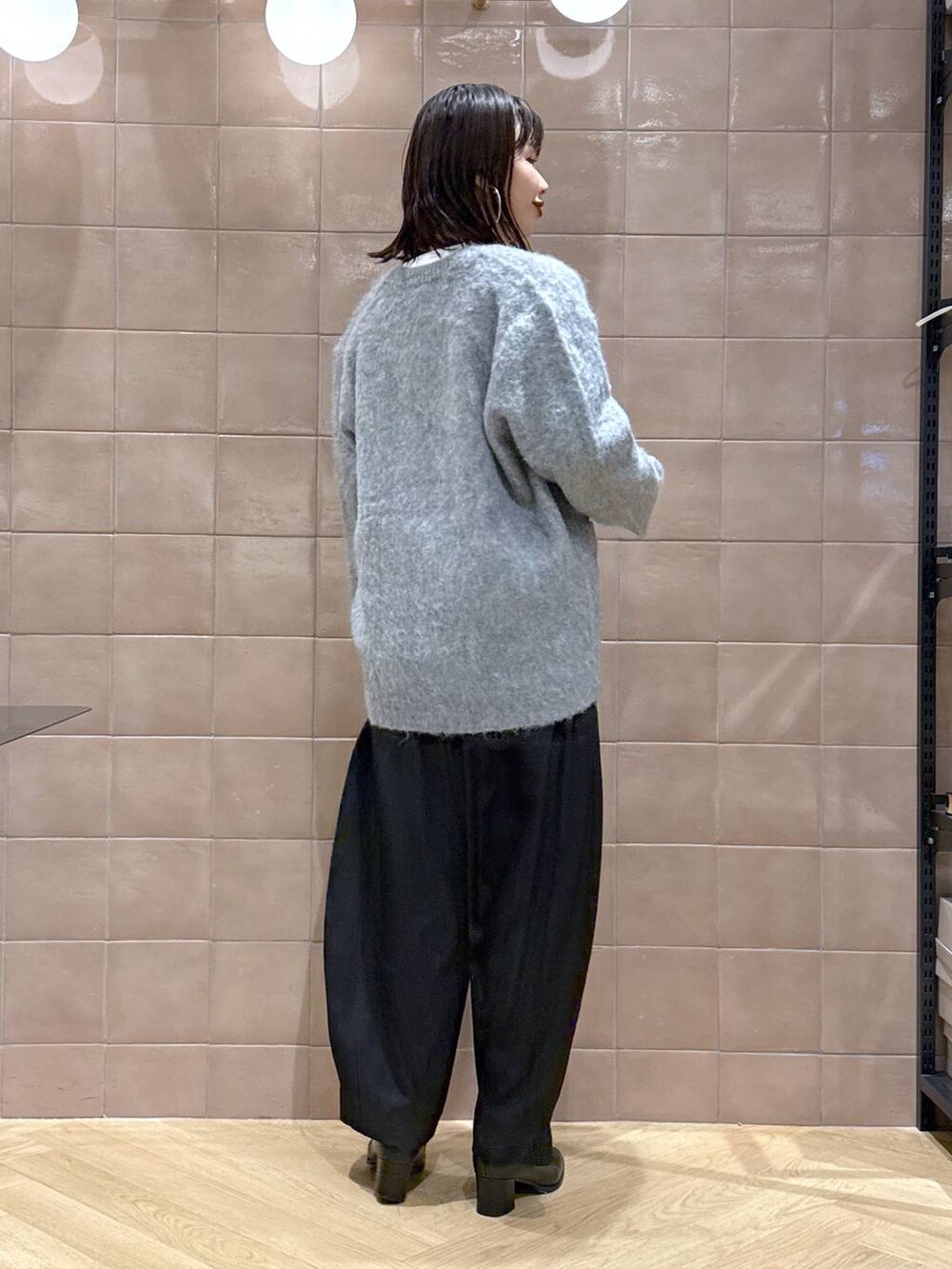 ブラック系のスラックス、グレー系のカーディガン/ボレロ、ホワイト系のTシャツ/カットソーを着用したレディースの冬コーディネートの4枚目の写真