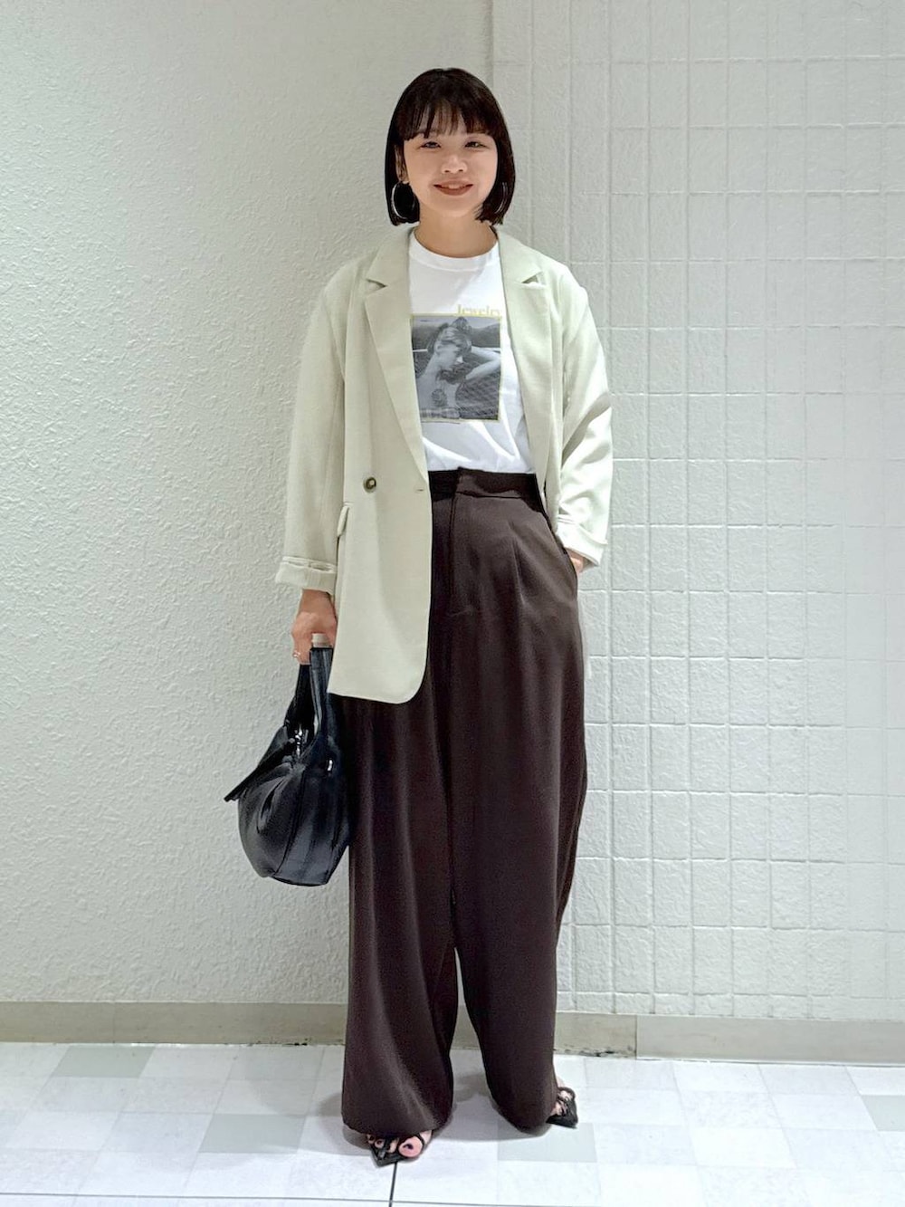 ブラック系のハンドバッグ、ブラック系のサンダル、ベージュ系のテーラードジャケットを着用したレディースの春コーディネートの2枚目の写真