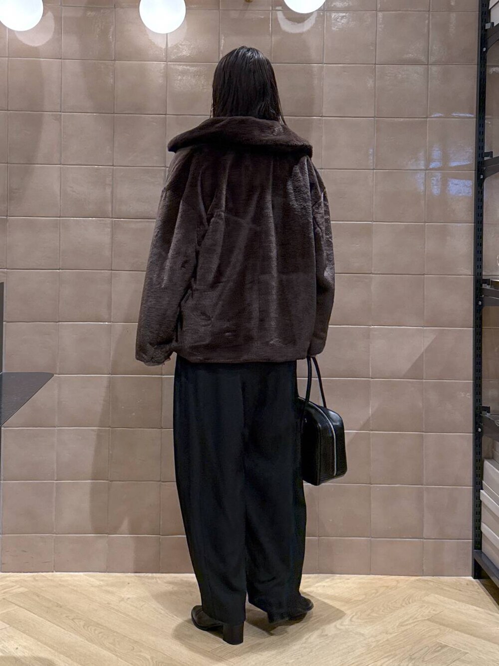 ブラック系のスラックス、ブラウン系のその他アウター、ブラック系のボストンバッグを着用したレディースの冬コーディネートの3枚目の写真