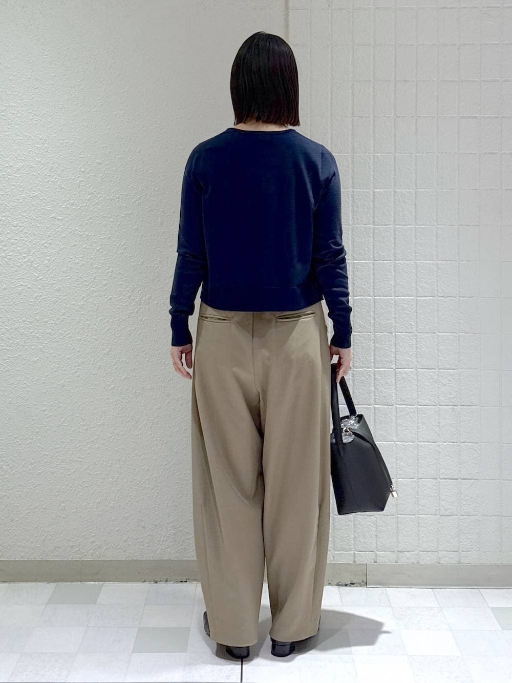 ベージュ系のスラックス、ブラック系のローファー、ブルー系のカーディガン/ボレロを着用したレディースの冬コーディネートの4枚目の写真