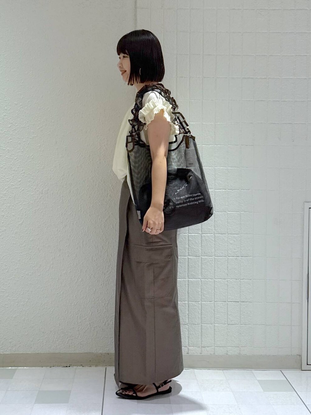 ブラック系のサンダル、ブラック系のトートバッグ、グリーン系のスカートを着用したレディースの夏コーディネートの5枚目の写真