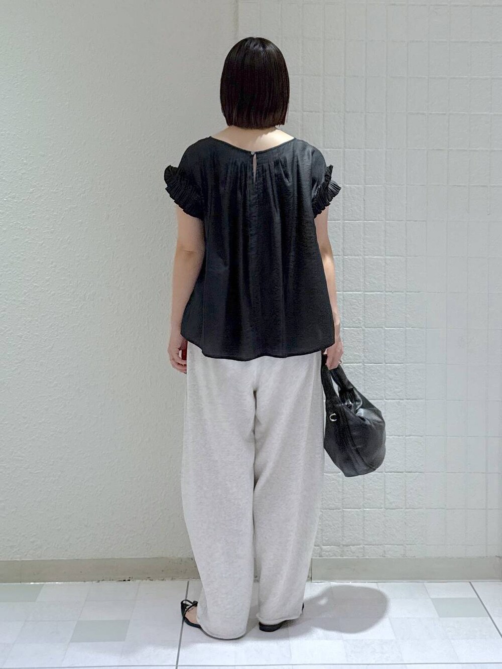 ブラック系のハンドバッグ、ブラック系のサンダル、グレー系のスウェットパンツを着用したレディースの夏コーディネートの4枚目の写真