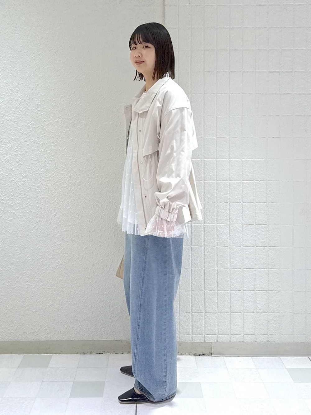 ブルー系のデニムパンツ、ベージュ系のブルゾン、ベージュ系のショルダーバッグを着用したレディースの春コーディネートの4枚目の写真