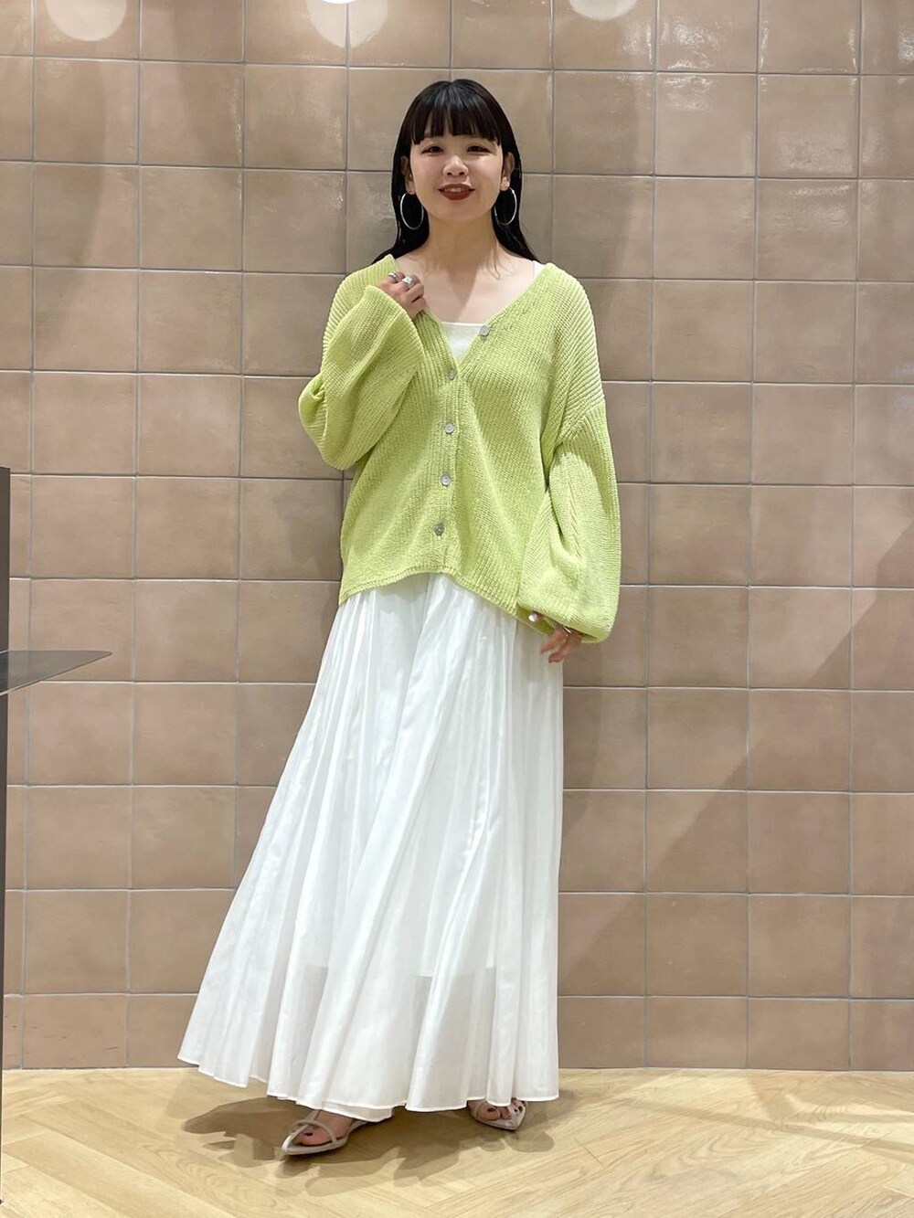ホワイト系のタンクトップ、ホワイト系のサンダル、イエロー系のカーディガン/ボレロを着用したレディースの春コーディネートの2枚目の写真