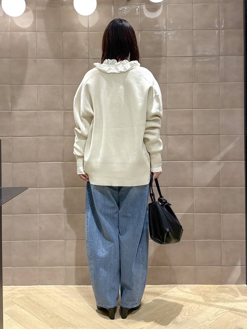 ブルー系のデニムパンツ、ホワイト系のカーディガン/ボレロ、ブラック系のショルダーバッグを着用したレディースの冬コーディネートの3枚目の写真