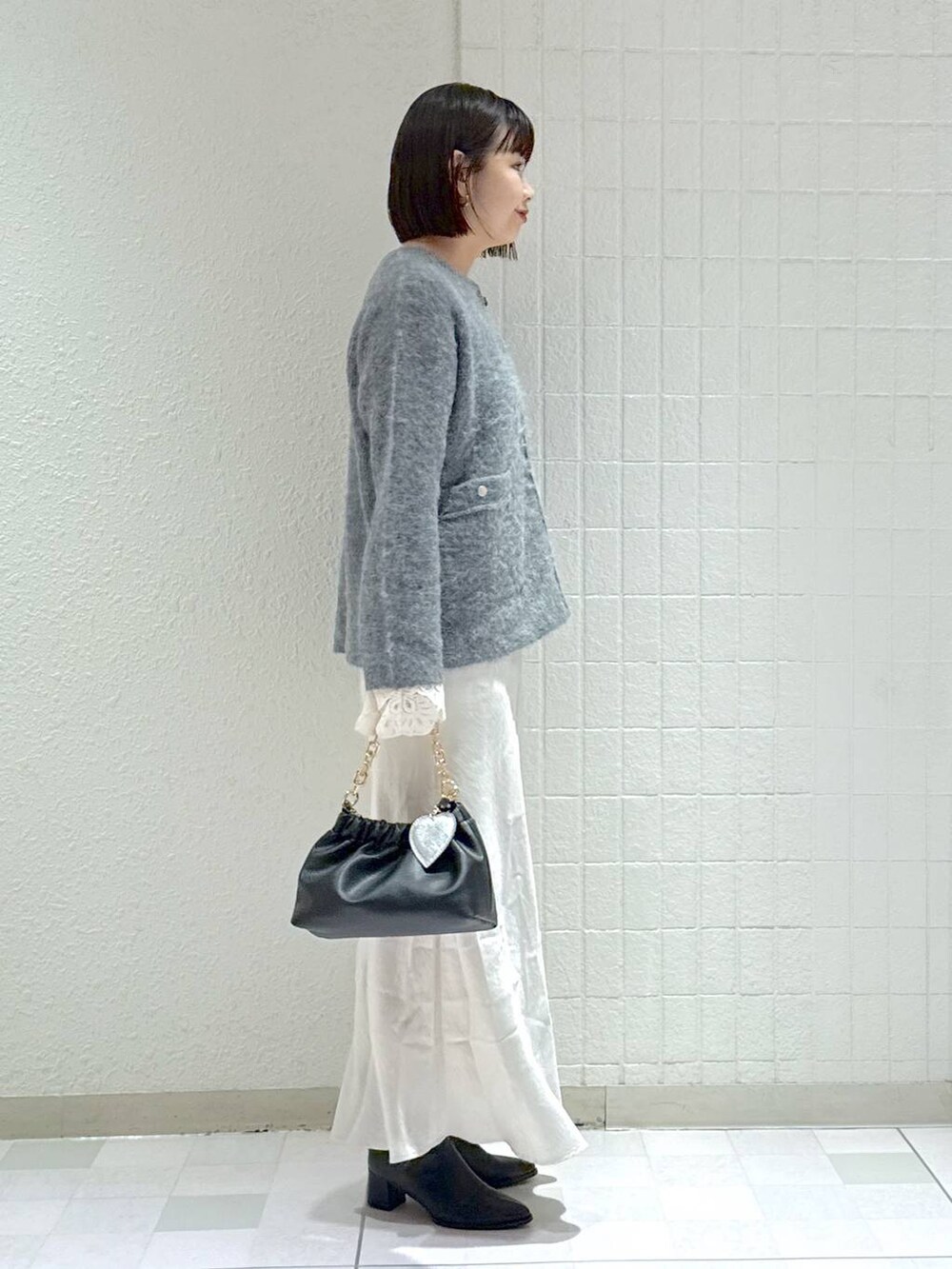 ブラック系のブーツ、グレー系のカーディガン/ボレロ、ホワイト系のスカートを着用したレディースの秋コーディネートの2枚目の写真