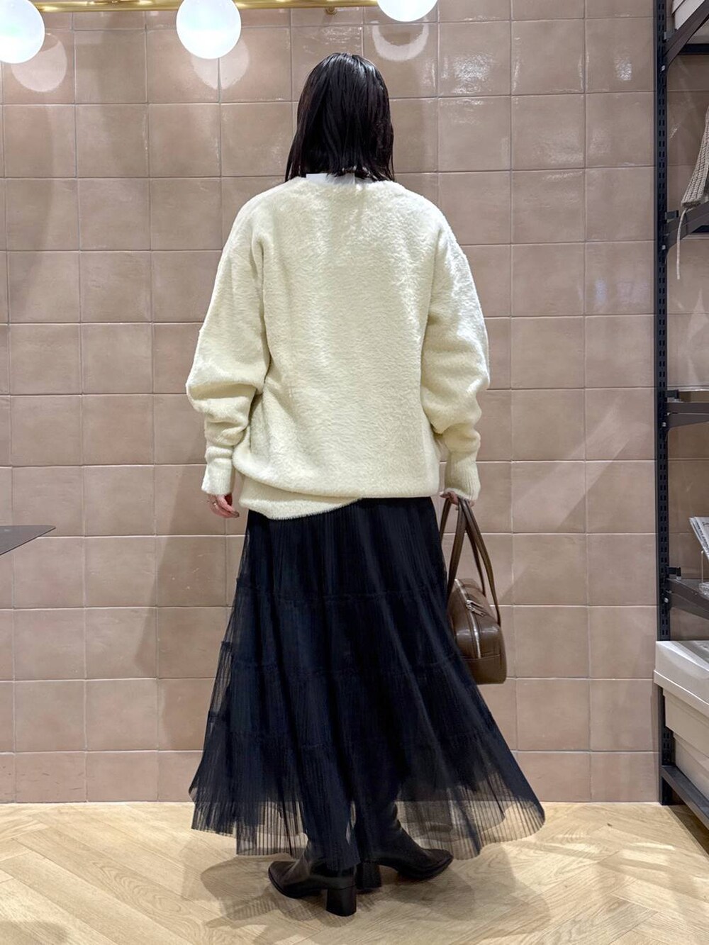 ホワイト系のTシャツ/カットソー、ブラック系のスカート、ベージュ系のカーディガン/ボレロを着用したレディースの冬コーディネートの2枚目の写真