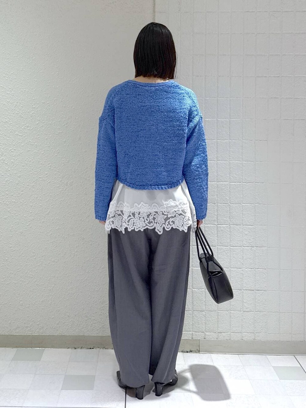 グレー系のスラックス、ホワイト系のキャミソール、ブラック系のパンプスを着用したレディースの春コーディネートの4枚目の写真