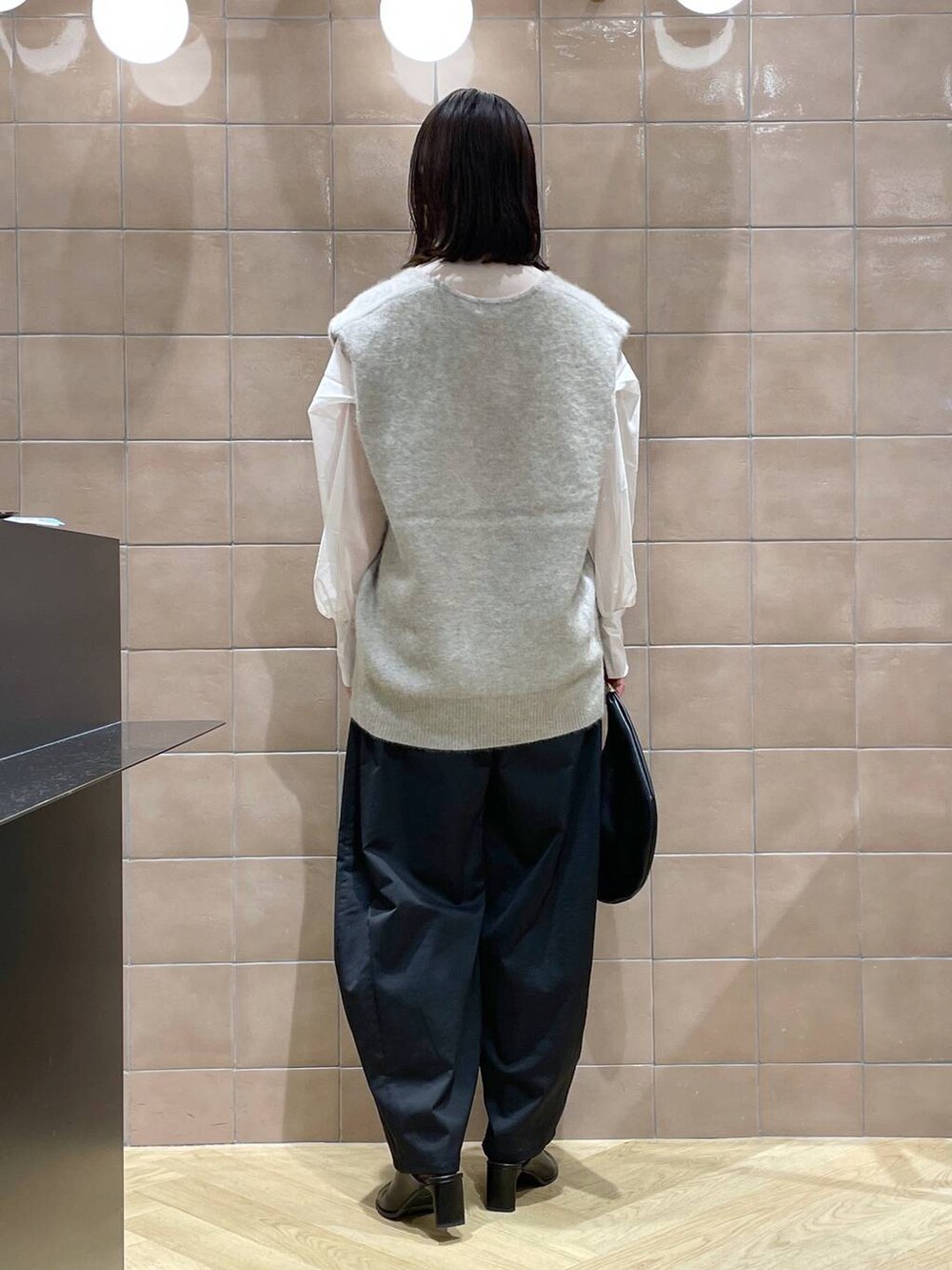 ブラック系のハンドバッグ、ベージュ系のベスト、ベージュ系のシャツ/ブラウスを着用したレディースの秋コーディネートの4枚目の写真