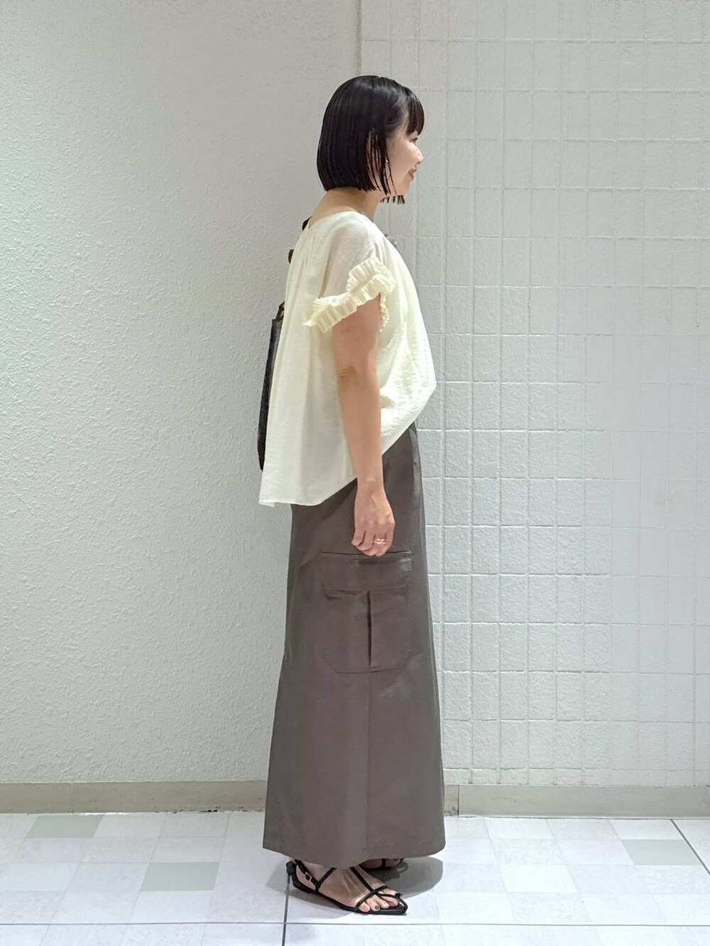 ブラック系のサンダル、ブラック系のトートバッグ、グリーン系のスカートを着用したレディースの夏コーディネートの3枚目の写真