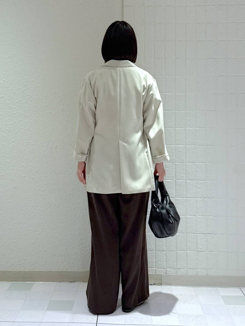 ブラック系のハンドバッグ、ブラック系のサンダル、ベージュ系のテーラードジャケットを着用したレディースの春コーディネートの4枚目の写真