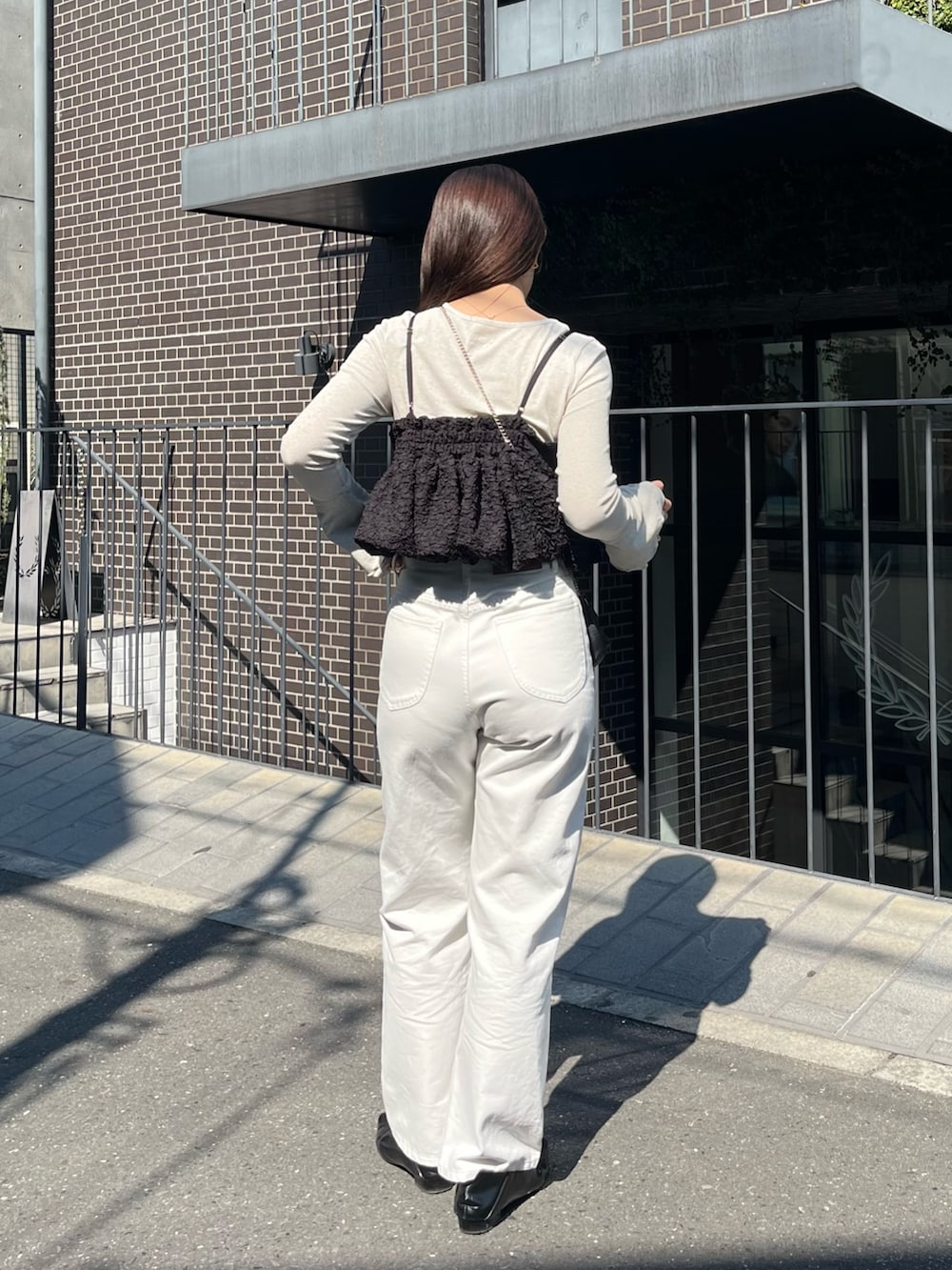 ベージュ系のTシャツ/カットソー、ブラック系のシャツ/ブラウス、ホワイト系のデニムパンツを着用したレディースの春コーディネートの4枚目の写真