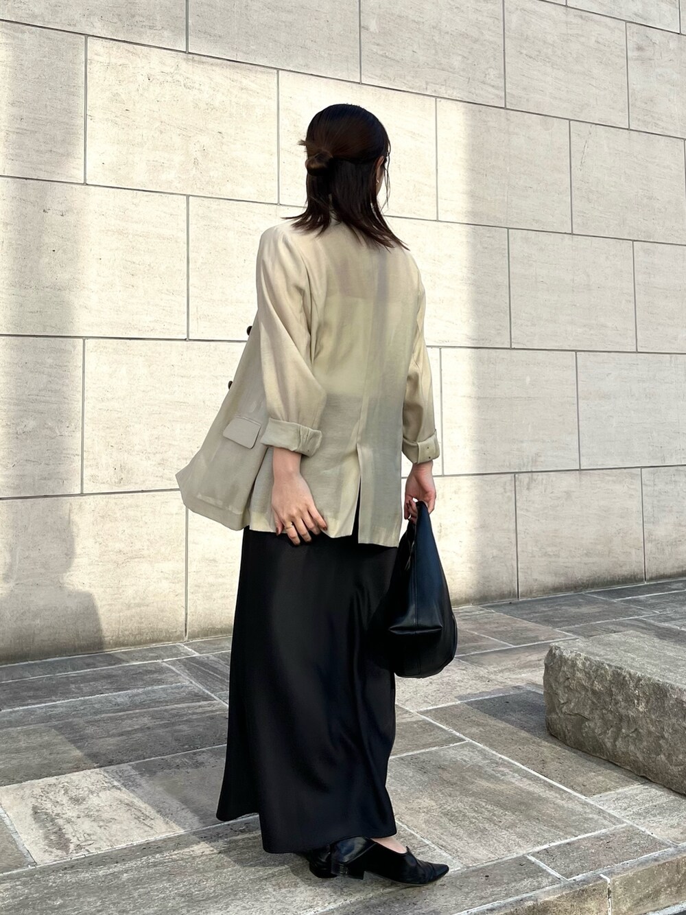 ホワイト系のキャミソール、ベージュ系のテーラードジャケット、ブラック系のスカートを着用したレディースの春コーディネートの5枚目の写真
