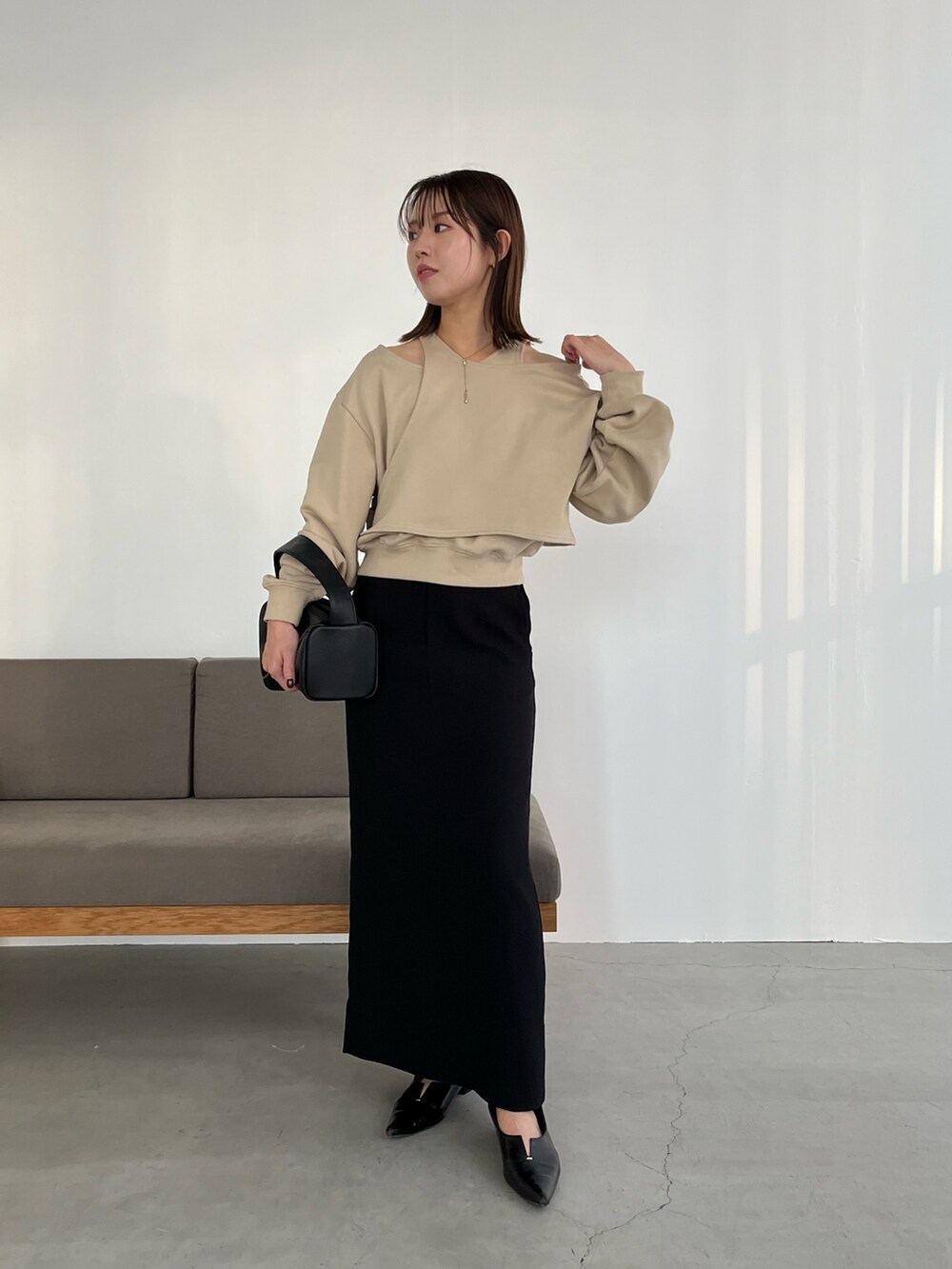 ベージュ系のスウェット、ブラック系のスカート、ブラック系のハンドバッグを着用したレディースの冬コーディネートの2枚目の写真