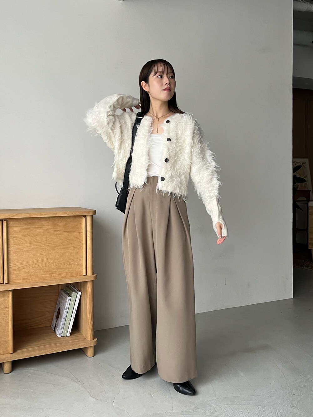 ホワイト系のカーディガン/ボレロ、ベージュ系のその他パンツ、ブラック系のショルダーバッグを着用したレディースの秋コーディネートの2枚目の写真