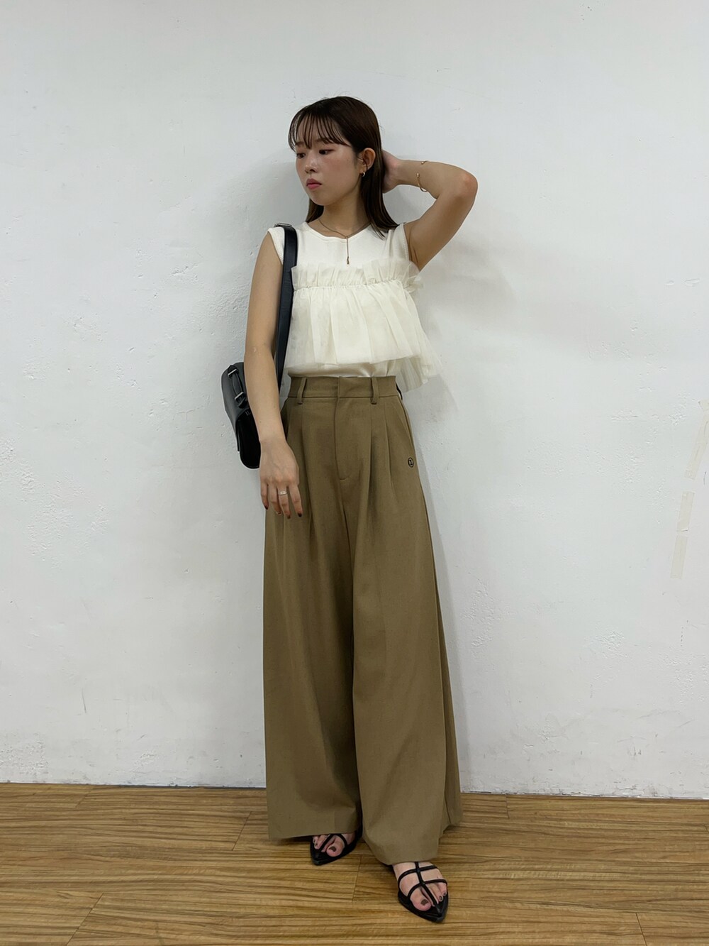 ホワイト系のニット/セーター、ベージュ系のその他パンツ、ブラック系のショルダーバッグを着用したレディースの夏コーディネートの3枚目の写真