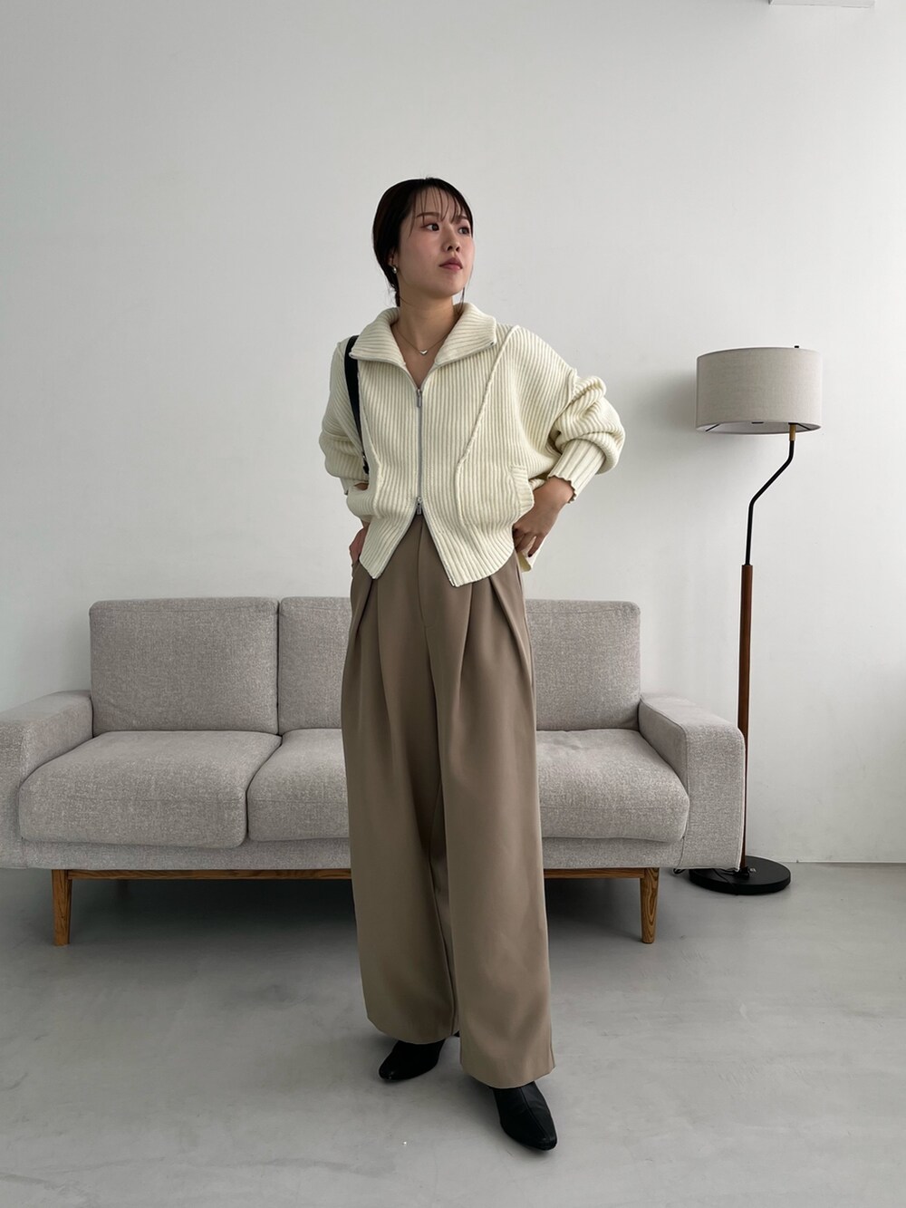 ベージュ系のその他パンツ、ホワイト系のカーディガン/ボレロ、ブラック系のショルダーバッグを着用したレディースの冬コーディネートの2枚目の写真