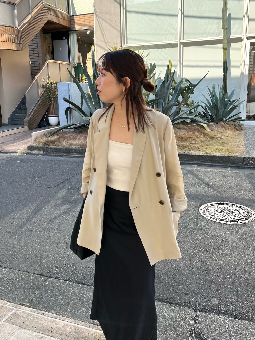 ホワイト系のキャミソール、ベージュ系のテーラードジャケット、ブラック系のスカートを着用したレディースの春コーディネートの3枚目の写真