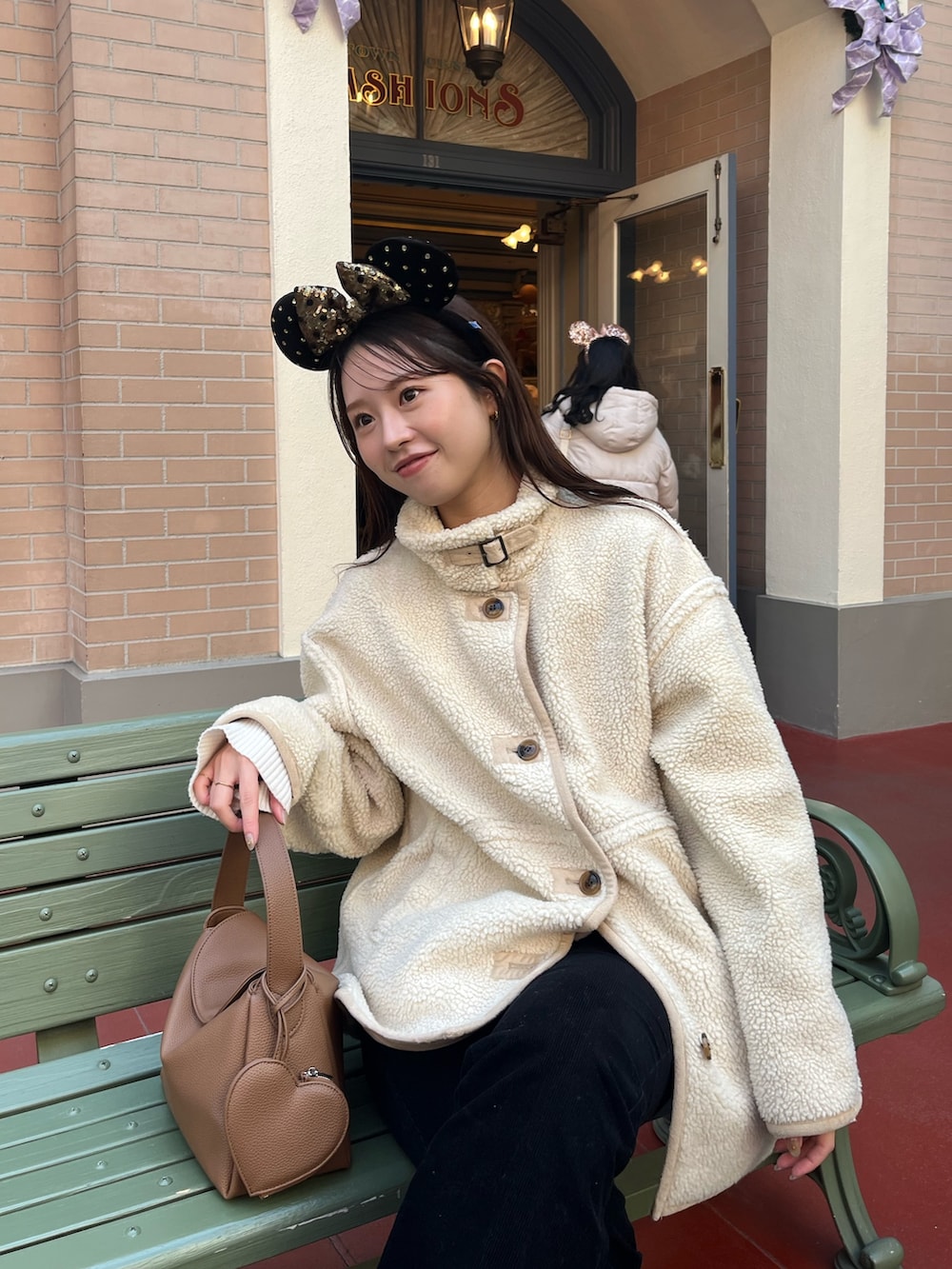 ホワイト系のその他アウター、ブラック系のその他パンツ、イエロー系のハンドバッグを着用したレディースの冬コーディネートの2枚目の写真