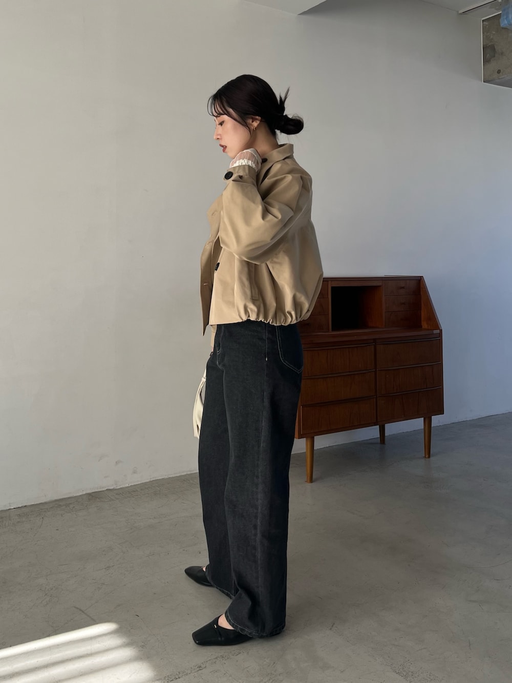 ブラック系のデニムパンツ、ブラック系のパンプス、ホワイト系のショルダーバッグを着用したレディースの冬コーディネートの4枚目の写真