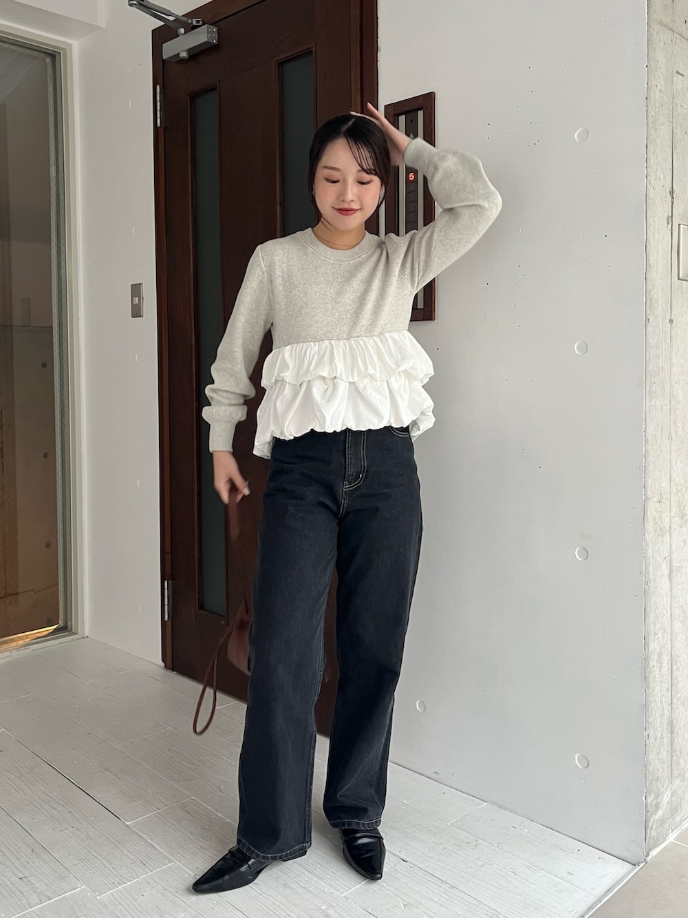 グレー系のニット/セーター、ブラック系のデニムパンツ、ブラック系のローファーを着用したレディースの冬コーディネートの4枚目の写真