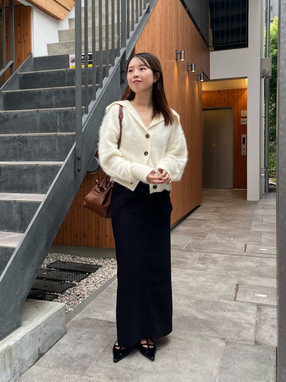 ホワイト系のカーディガン/ボレロ、ブラック系のパンプス、ブラック系のスカートを着用したレディースの秋コーディネートの2枚目の写真