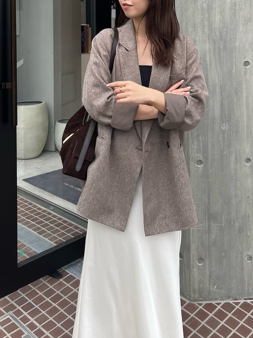 ベージュ系のテーラードジャケット、ホワイト系のスカート、ブラウン系のショルダーバッグを着用したレディースの冬コーディネートの4枚目の写真