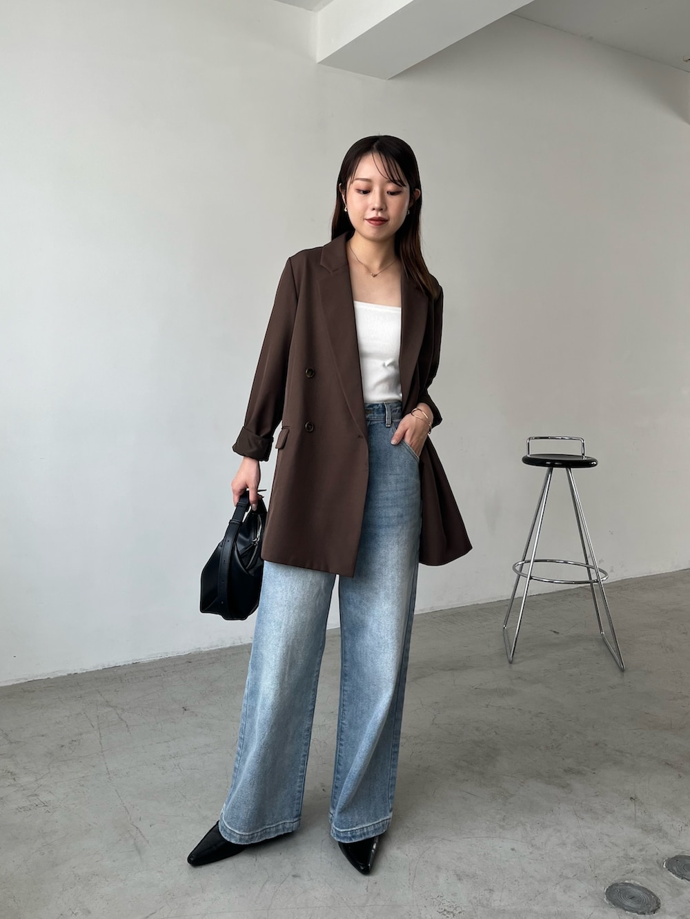 ブラウン系のテーラードジャケット、ブルー系のデニムパンツ、ブラック系のローファーを着用したレディースの秋コーディネートの2枚目の写真