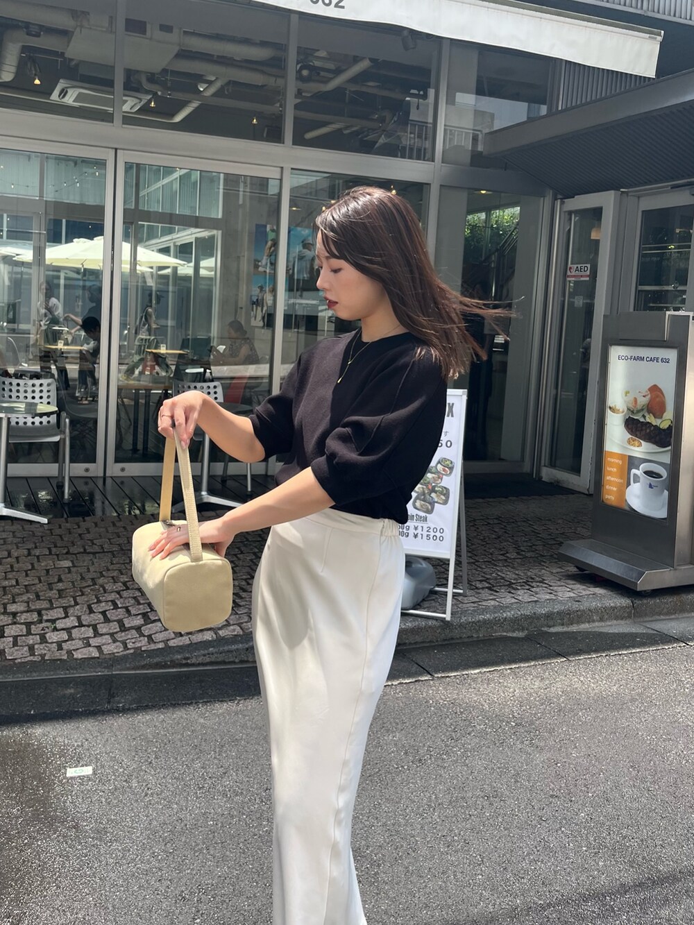 ブラック系のニット/セーター、ホワイト系のスカート、ブラック系のサンダルを着用したレディースの夏コーディネートの2枚目の写真
