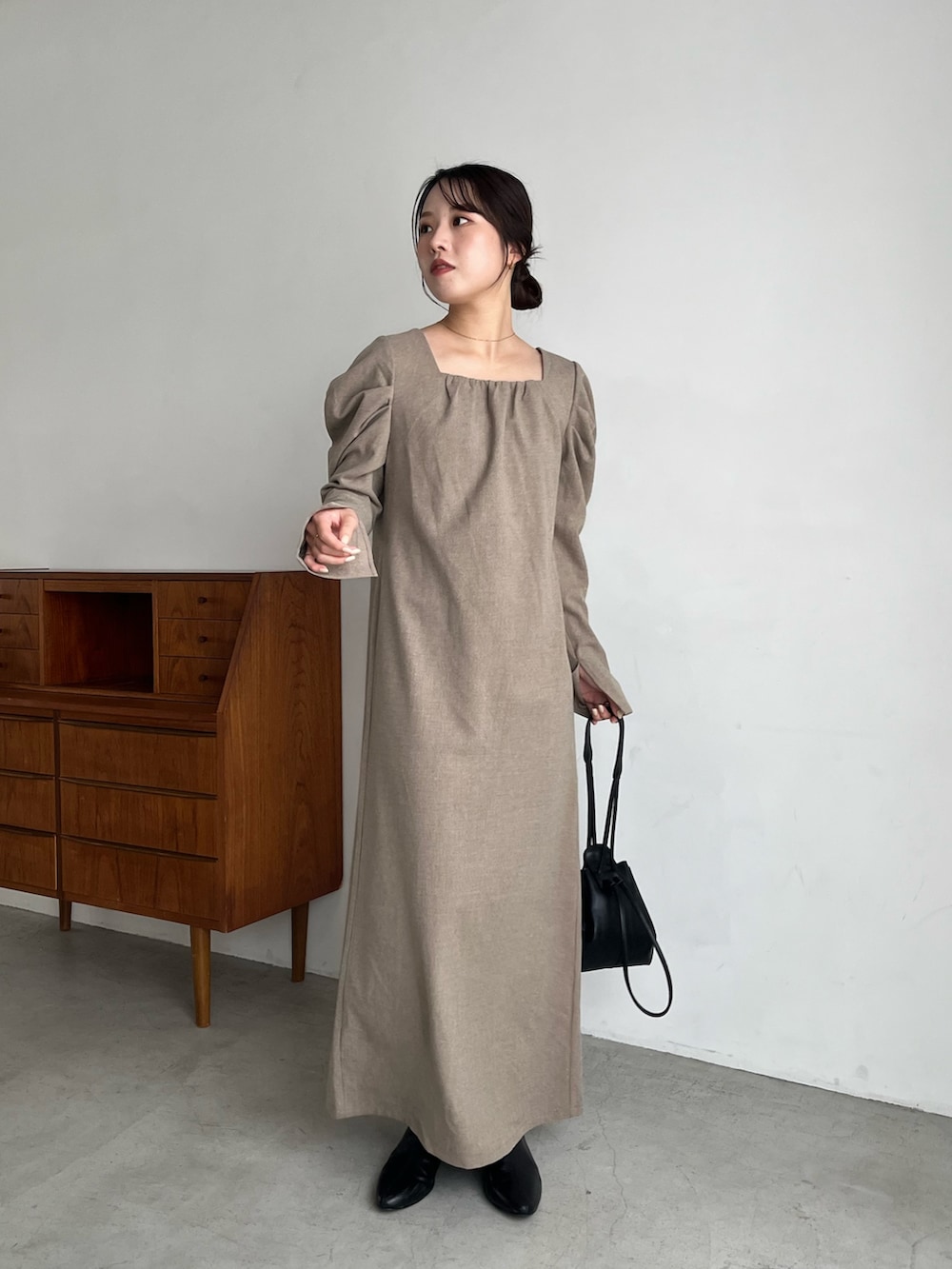 ベージュ系のワンピース、ブラック系のブーツ、ブラック系のショルダーバッグを着用したレディースの冬コーディネートの2枚目の写真