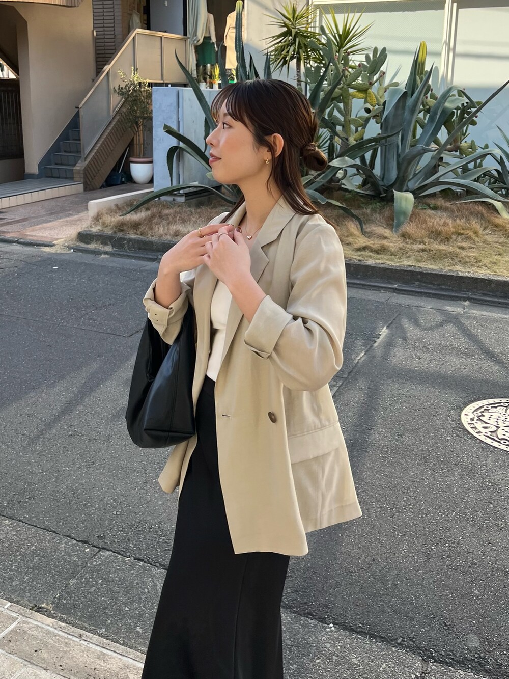 ホワイト系のキャミソール、ベージュ系のテーラードジャケット、ブラック系のスカートを着用したレディースの春コーディネートの4枚目の写真