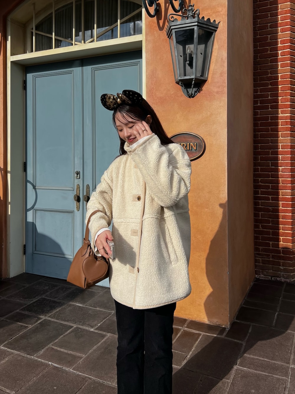 ホワイト系のその他アウター、ブラック系のその他パンツ、イエロー系のハンドバッグを着用したレディースの冬コーディネートの3枚目の写真