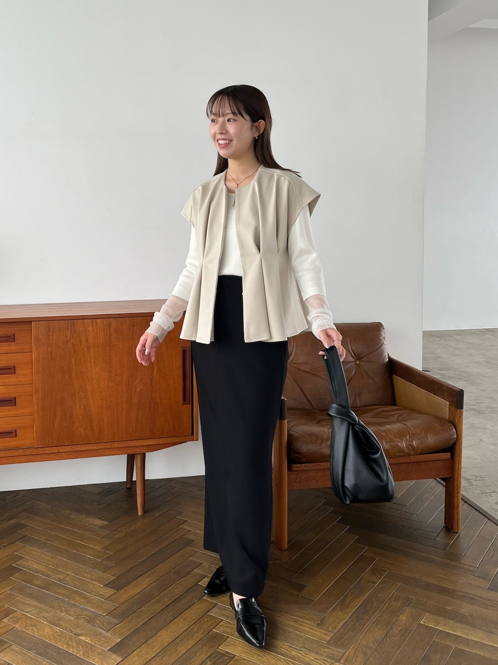 ホワイト系のニット/セーター、ブラック系のハンドバッグ、ブラック系のパンプスを着用したレディースの秋コーディネートの3枚目の写真