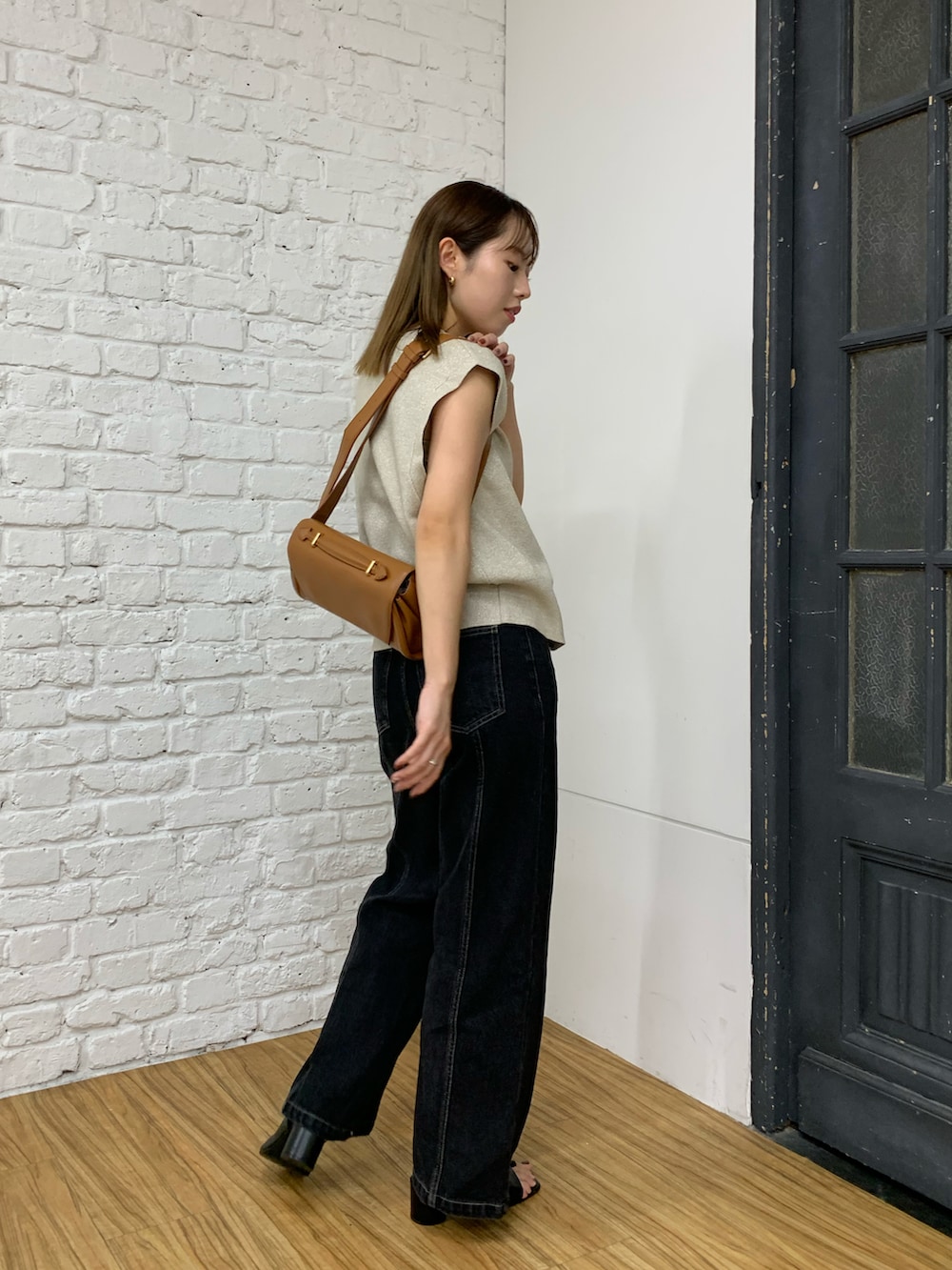 ベージュ系のニット/セーター、ブラック系のデニムパンツ、ブラック系のショルダーバッグを着用したレディースの秋コーディネートの3枚目の写真