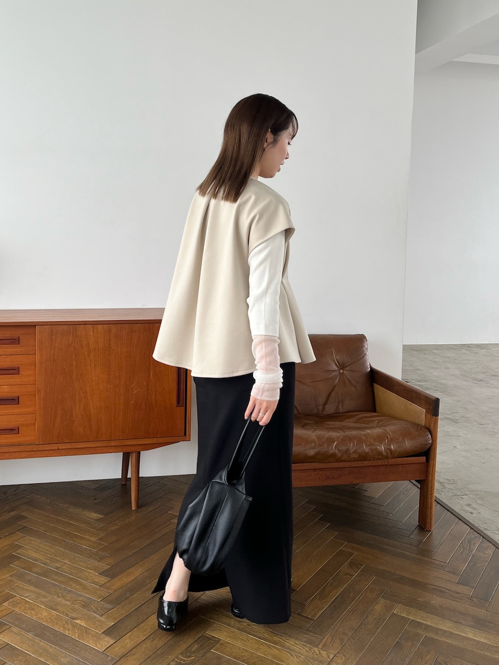 ホワイト系のニット/セーター、ブラック系のハンドバッグ、ブラック系のパンプスを着用したレディースの秋コーディネートの4枚目の写真