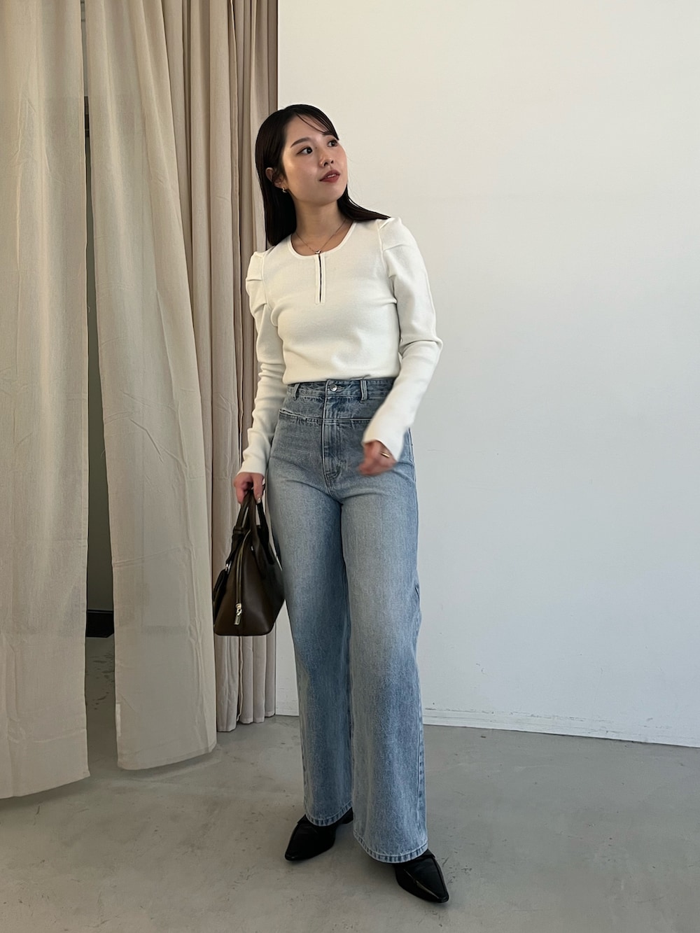 ブルー系のデニムパンツ、ブラック系のローファー、ブラウン系のショルダーバッグを着用したレディースの冬コーディネートの3枚目の写真