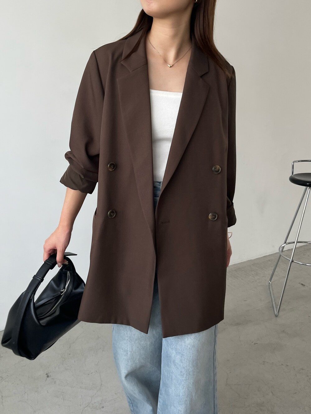 ブラウン系のテーラードジャケット、ブルー系のデニムパンツ、ブラック系のローファーを着用したレディースの秋コーディネートの3枚目の写真